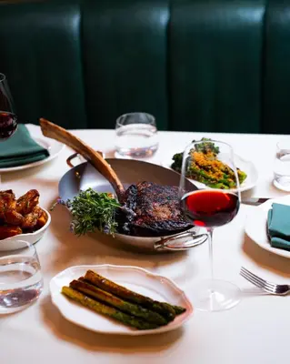 a table with a plate of food and a glass of wine at The Georgian Hotel in Los Angeles