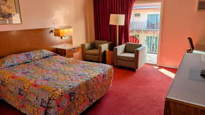 a hotel room with a bed and a chair at Royal Century Hotel at LAX in Inglewood