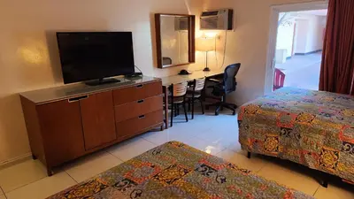 a hotel room with a bedroom with two beds and a flat screen tv at Royal Century Hotel at LAX in Inglewood