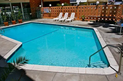 a large blue swimming pool with two chairs in it at Royal Century Hotel at LAX in Inglewood