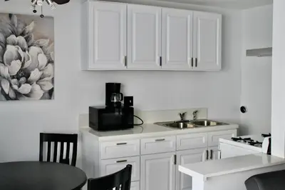 a kitchen with white cabinets and a sink and a table at Chic Apartment in Los Angeles