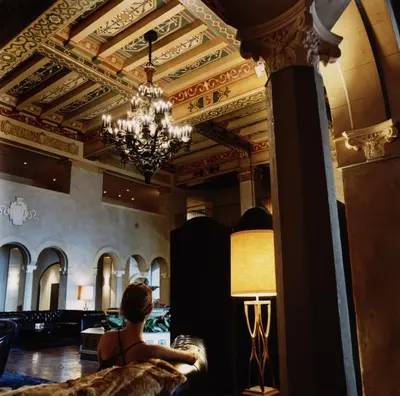 a woman sitting in a room with a chandelier at The Hollywood Roosevelt in Los Angeles