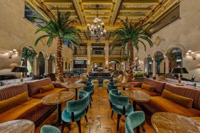 a lobby with tables and chairs and palm trees at The Hollywood Roosevelt in Los Angeles