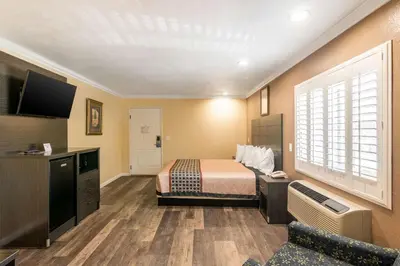 a hotel room with a bed and a flat screen tv at Rodeway Inn Artesia Cerritos in Artesia