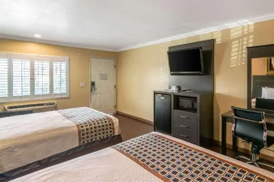 a hotel room with two beds and a flat screen tv at Rodeway Inn Artesia Cerritos in Artesia