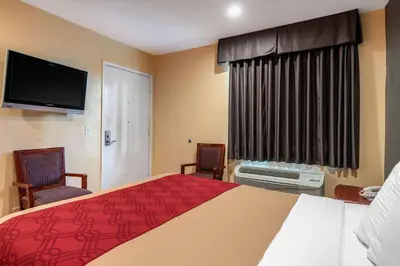 a hotel room with a bed and two chairs and a television at Rodeway Inn Carson - Los Angeles South in Carson
