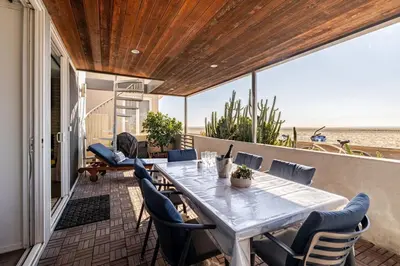 a table and chairs on a balcony with the beach at Oceanfront Oasis in Long Beach