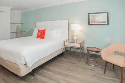 a bedroom with a bed and a table and a chair at Pasadena Rose & Crown Hotel in Pasadena