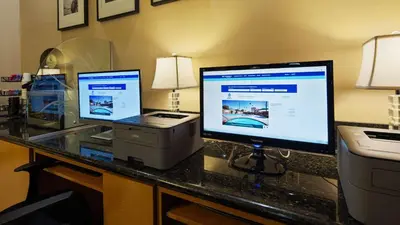 a desk with two computer monitors and a printer at Best Western Pasadena Inn in Pasadena
