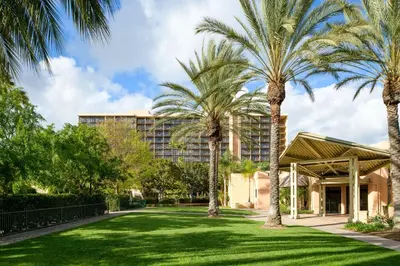 a building with palm trees in front of a yard at Sheraton Park Hotel at the Anaheim Resort in Anaheim