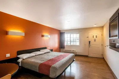 a bedroom with a bed with an orange wall at Motel 6 Bell Gardens, CA - Los Angeles in Bell Gardens