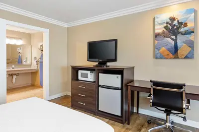 a hotel room with a desk and a tv and a bed at Best Western China Lake Inn in Ridgecrest