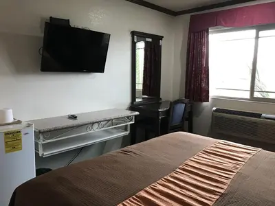 a bedroom with a bed and a television on the wall at Starlight Inn Canoga Park in Canoga Park