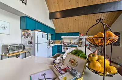 a kitchen with blue cabinets and a table with fruit at Lake Arrowhead A-Frame House with Private Hot Tub! in Lake Arrowhead