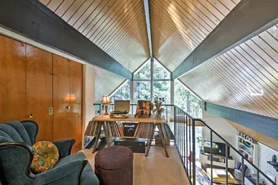 an attic living room with a large window and a desk at Lake Arrowhead A-Frame House with Private Hot Tub! in Lake Arrowhead