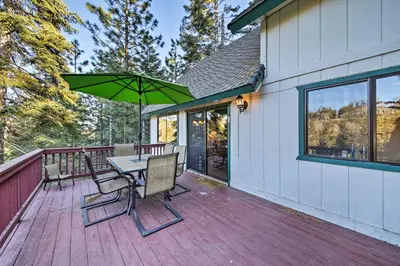 a wooden deck with a table and chairs and an umbrella at Spacious Lake Arrowhead Home with 2 Decks and Views in Lake Arrowhead