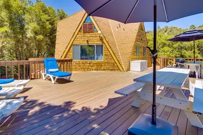 a deck with a cabin with a picnic table and an umbrella at Star House Unique Home with 360 Mountain Views! in Pine Mountain Club