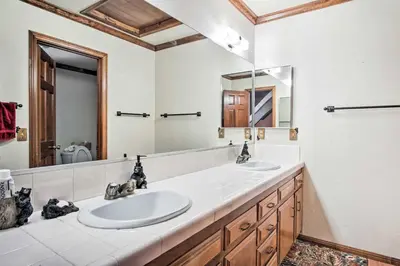 a bathroom with two sinks and a large mirror at 5 Mi to Lake Arrowhead Village Cabin with Game Room in Lake Arrowhead
