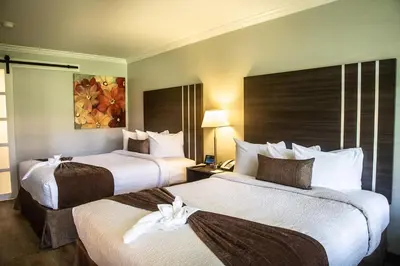 a hotel room with two beds and a painting on the wall at Palm Garden Hotel in Thousand Oaks