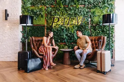 a man and woman sitting in leather chairs with luggage at Palm Garden Hotel in Thousand Oaks