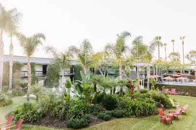 a resort with a garden with red chairs and palm trees at Palm Garden Hotel in Thousand Oaks