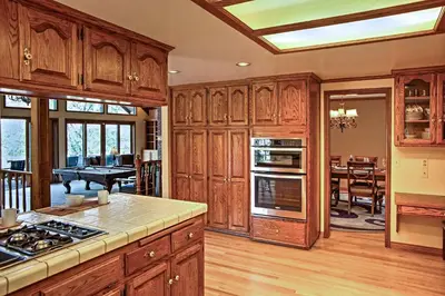 a kitchen with wooden cabinets and a dining room at Lake Arrowhead House with Lake Views and Wet Bar! in Lake Arrowhead