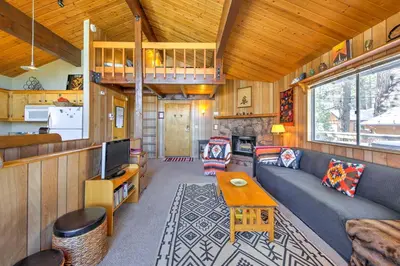a living room with a couch and a table at Cabin with Mtn Views and Deck, 5 Min To Arrowbear Lake! in Arrowbear Lake