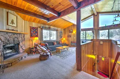 a living room with a stone fireplace in a house at Cabin with Mtn Views and Deck, 5 Min To Arrowbear Lake! in Arrowbear Lake