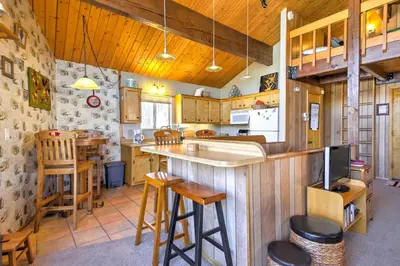 a kitchen with a bar and some wooden stools at Cabin with Mtn Views and Deck, 5 Min To Arrowbear Lake! in Arrowbear Lake