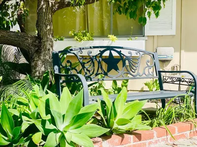a bench sitting in a garden next to a tree at GREAT FOR BUSINESS & FAMILY TRIPS 3BD 2BA close to DESNEYLAND, FREE PARKING in Orange