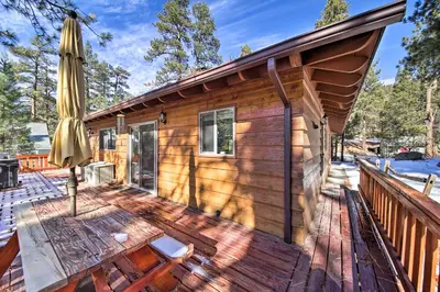 a cabin with a deck with an umbrella at Walk to Lake Rustic Home with Deck in Fawnskin in Fawnskin