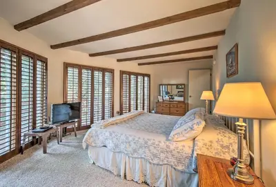 a bedroom with a bed and a tv and windows at Lake Arrowhead Cabin with Deck and Scenic Forest Views in Lake Arrowhead