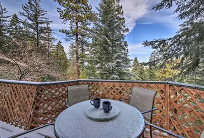 a table and chairs on a balcony with trees at Lake Arrowhead Cabin with Deck and Scenic Forest Views in Lake Arrowhead