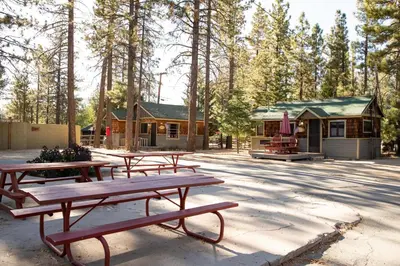 a group of picnic tables in front of a cabin at Juniper Lakeside Couples Resort Cabin by Big Bear Vacations in Big Bear Lake