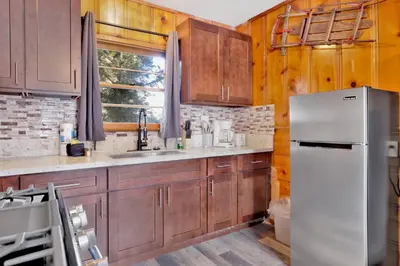 a kitchen with wooden cabinets and a white refrigerator at Juniper Lakeside Couples Resort Cabin by Big Bear Vacations in Big Bear Lake