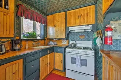 a kitchen with wooden cabinets and a white stove top oven at Walk to Lake Cabin with Deck and Views in Fawnskin in Fawnskin