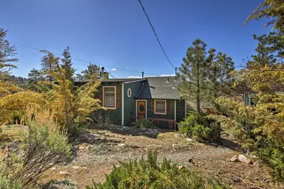 a green house in the middle of a yard at Walk to Lake Cabin with Deck and Views in Fawnskin in Fawnskin