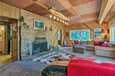 a living room with a stone fireplace and a couch at Expansive Retreat with Deck, Game Room and Lake Views! in Lake Arrowhead