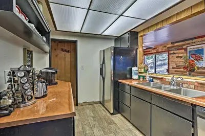 a kitchen with a sink and a refrigerator at Expansive Retreat with Deck, Game Room and Lake Views! in Lake Arrowhead