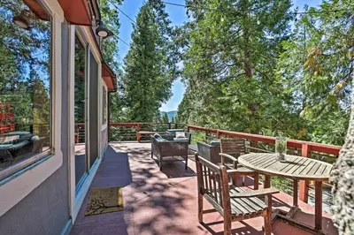 a patio with a table and chairs on a balcony at Expansive Retreat with Deck, Game Room and Lake Views! in Lake Arrowhead