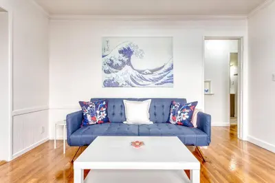 a living room with a blue couch and a white table at New Beach Jewel Bungalow in Long Beach