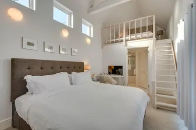 a bedroom with a large white bed and a staircase at Beachfront Malibu House with Sauna and Ocean-View Deck in Malibu