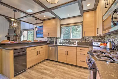 a large kitchen with wooden cabinets and stainless steel appliances at Bikes and Game Room Lovely Lake Arrowhead Home! in Lake Arrowhead