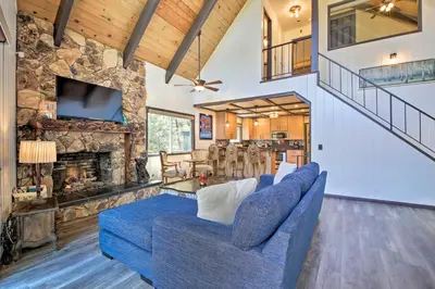 a living room with a blue couch and a stone fireplace at Bikes and Game Room Lovely Lake Arrowhead Home! in Lake Arrowhead