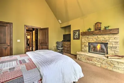 a bedroom with a stone fireplace and a bed at Incredible Lake Arrowhead Home with Views and Decks! in Lake Arrowhead