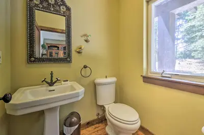 a bathroom with a toilet and a sink and a mirror at Incredible Lake Arrowhead Home with Views and Decks! in Lake Arrowhead