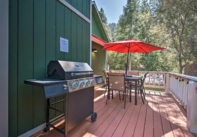 a grill and a table on a deck with an umbrella at Spacious Pine Mtn Club Cabin with Game Room and Deck in Pine Mountain Club