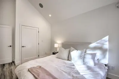 a white bedroom with a large white bed with pillows at Half-Mi to Big Bear Lake Modern Home with Deck in Big Bear Lake
