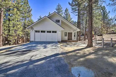 a white house with a garage in the woods at Half-Mi to Big Bear Lake Modern Home with Deck in Big Bear Lake