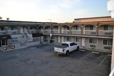 a white truck parked in a parking lot in front of a building at Bell Gardens Inn Los Angeles - Bell Gardens in Bell Gardens